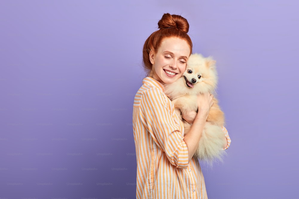 romantic girl falling in love of her pet. close up portrait, isolated blue background, studio shot