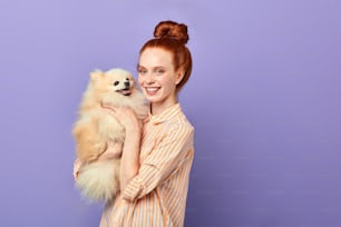 overjoyed girl takes care of her pet, close up portrait, isolated blue background, studio shot