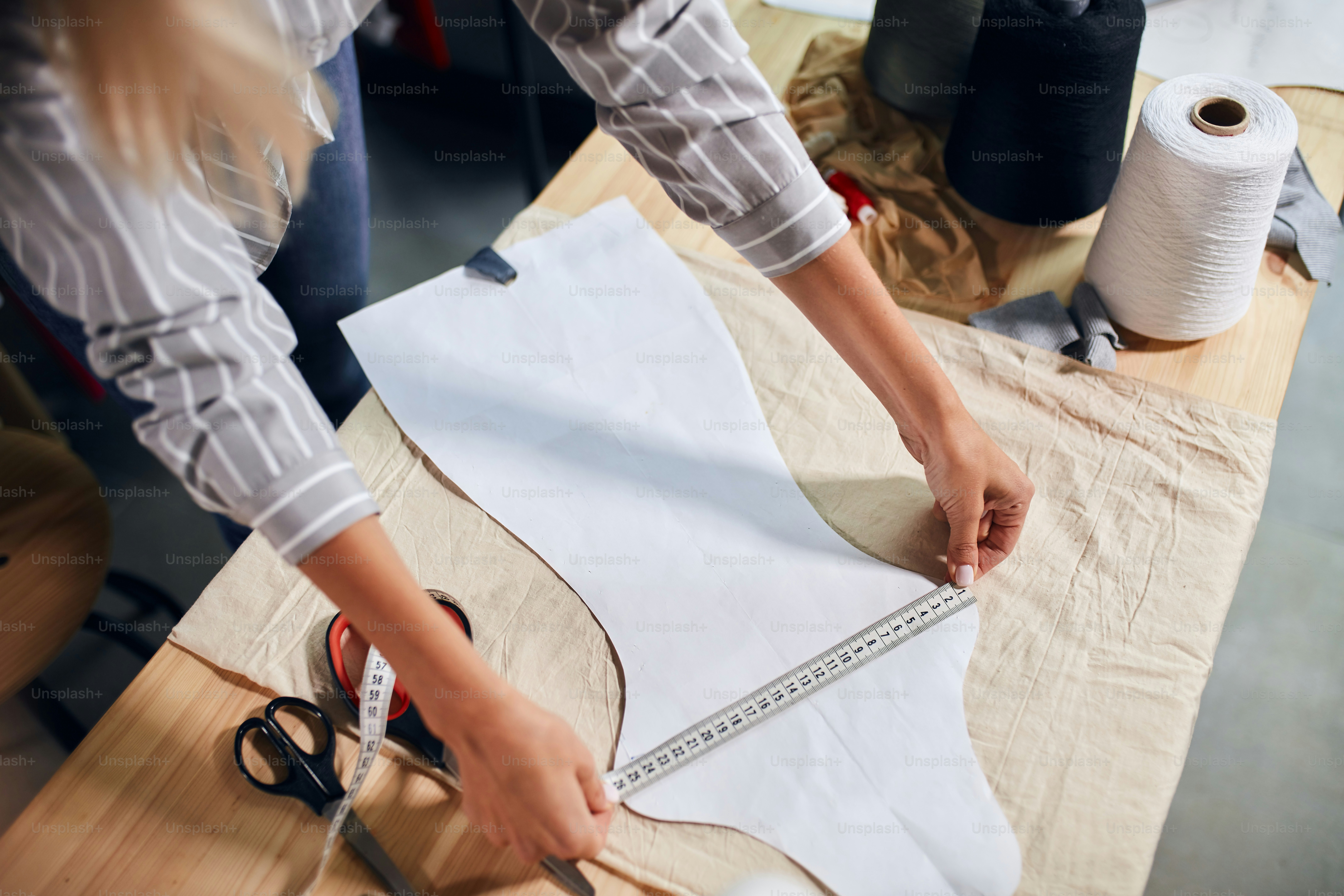 dressmaker working with measuring tape, close up cropped photo