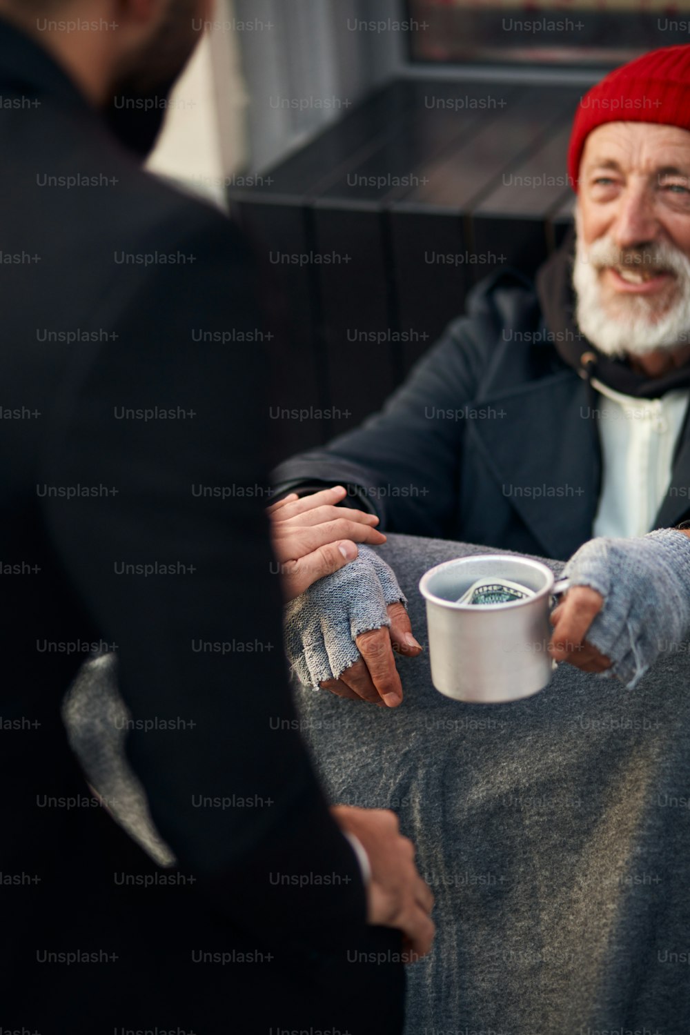 Hombre amable ayuda mendigo macho sentado en la calle mendigando, clima frío. Lástima masculina necesita dinero, comida, refugio. Mendigo con guantes grises