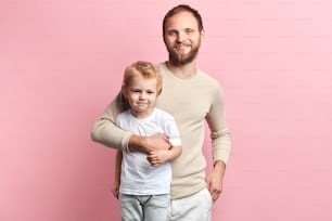 Glücklicher Papa, der sein Kind umarmt, isolierter rosa Hintergrund, Studioaufnahme, Beziehung. Nahaufnahme Porträt, Studioaufnahme.