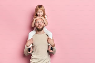 young good looking kind fatherhaving fun with his little child, close up portrait, isolated pink background, studio shot. family, happy parenthood