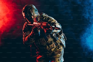 safety and protection concept. young man work as military man protecting country, wearing military forces clothes and holding gun in smoky UV space