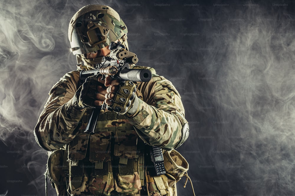 Soldat der Spezialeinheit mit Maschinengewehr und militärischer Ausrüstung im verrauchten Raum