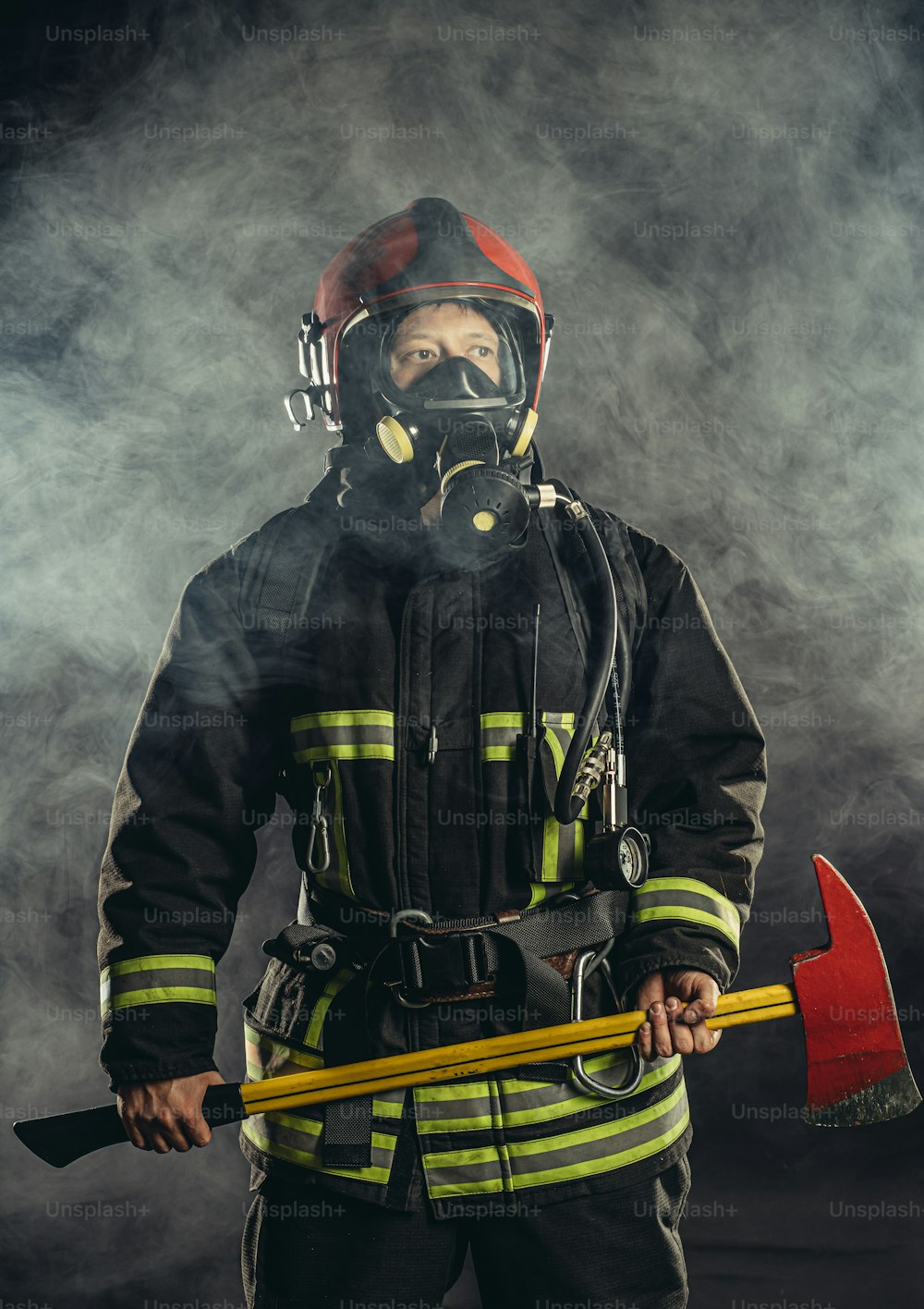 Bombero fuerte y seguro de sí mismo salvando y protegiendo del fuego, usando casco protector y traje, trabajando en la estación de bomberos