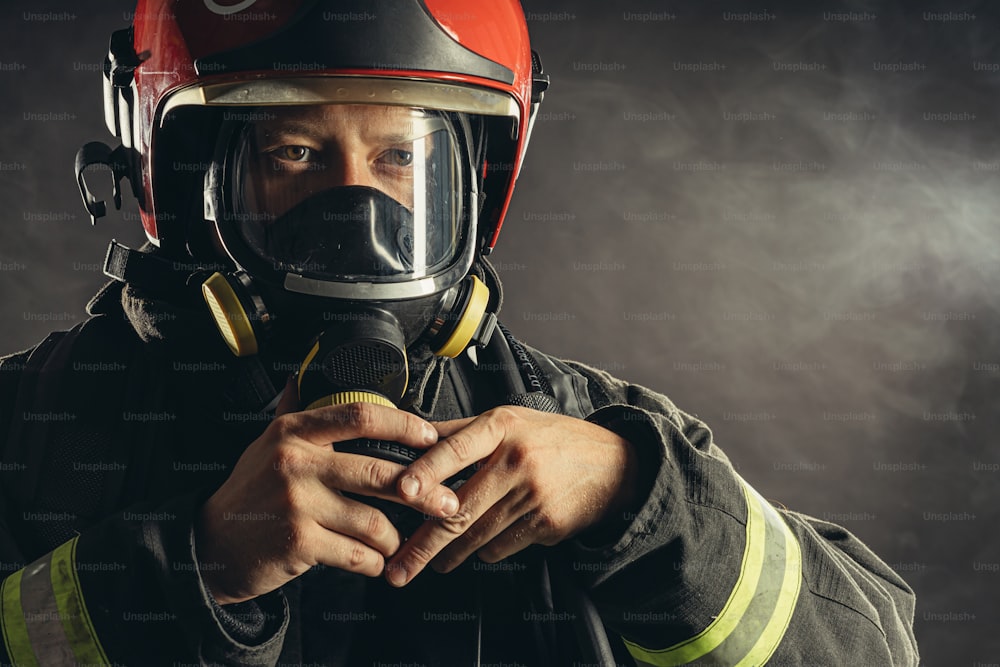 jovem bombeiro caucasiano com capacete na cabeça olhar para o fogo sem perigo, pronto para proteger a todos