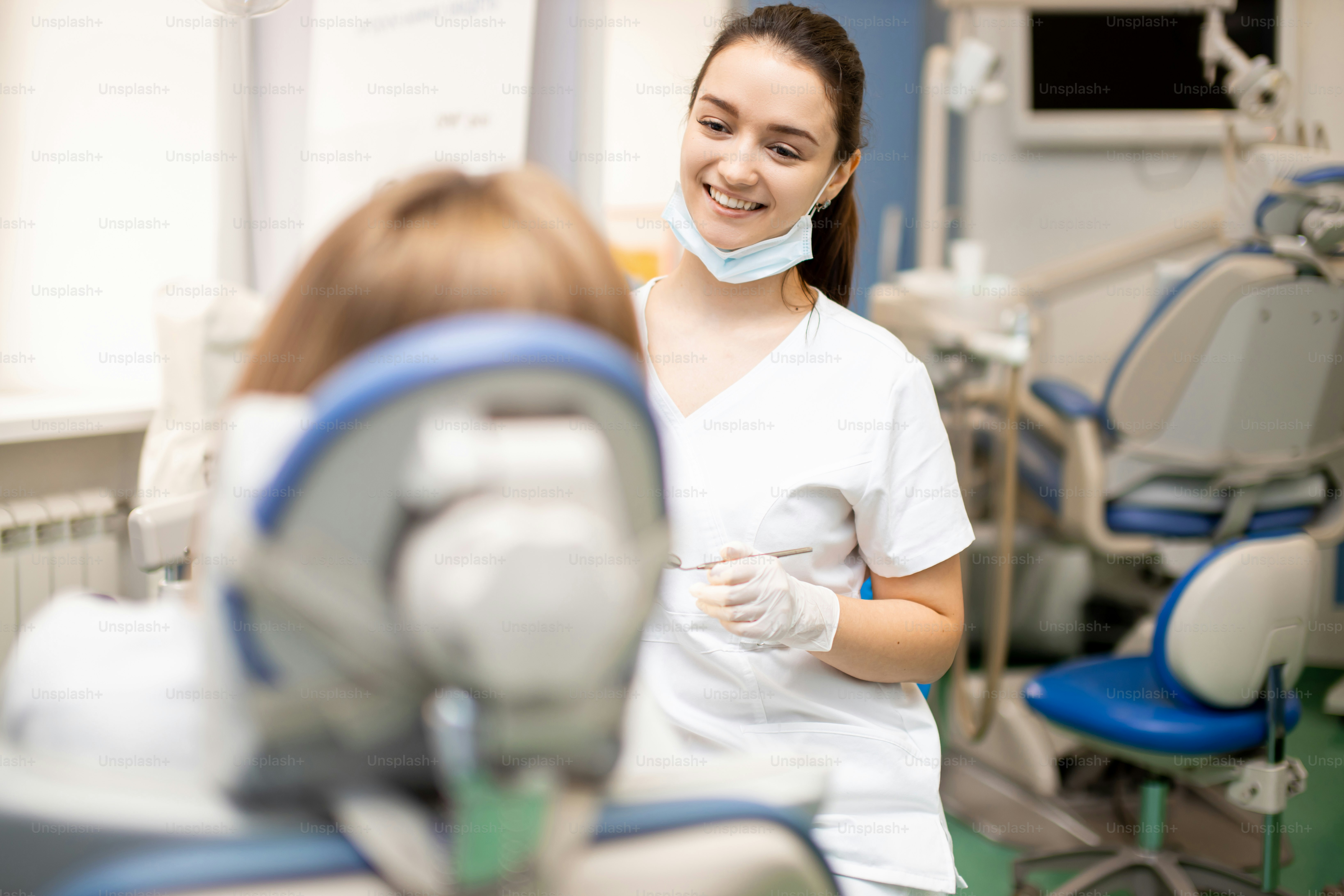 Dentiste professionnel attentif en uniforme blanc traitant les dents du patient, faisant un sourire parfait pour les patients, utilisant un équipement médical