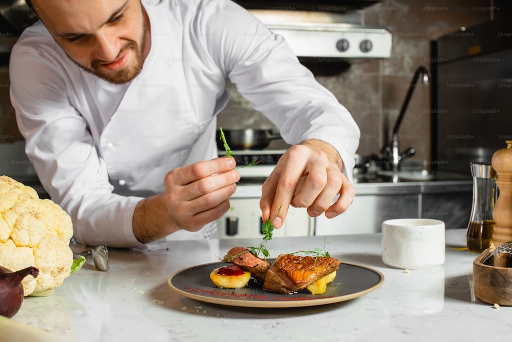 caucasian chef-cook finishing delicious dish in the kitchen of restaurant. expert in culinary. food concept