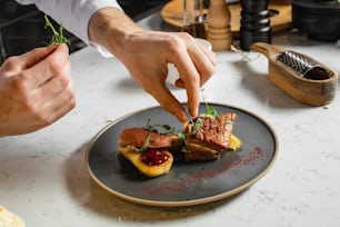 close-up professional chef-cook decorating dish in the kitchen. man in white apron makes the finishing touch on the dish. culinary, food, restaurant, gourmet concept