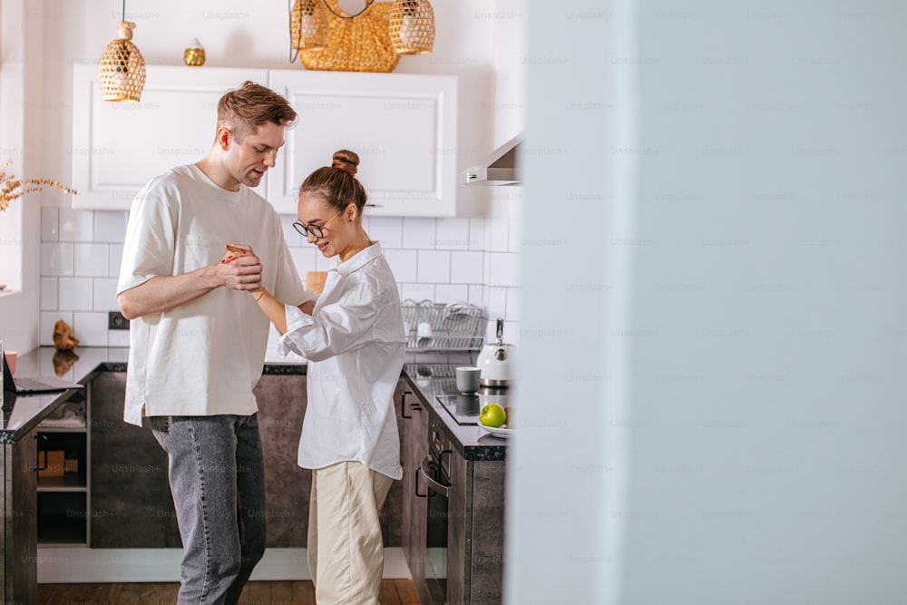 young caucasian married couple in love, dance in kitchen. love, happy relationships concept. couple in domestic clothes feel each other in every movement