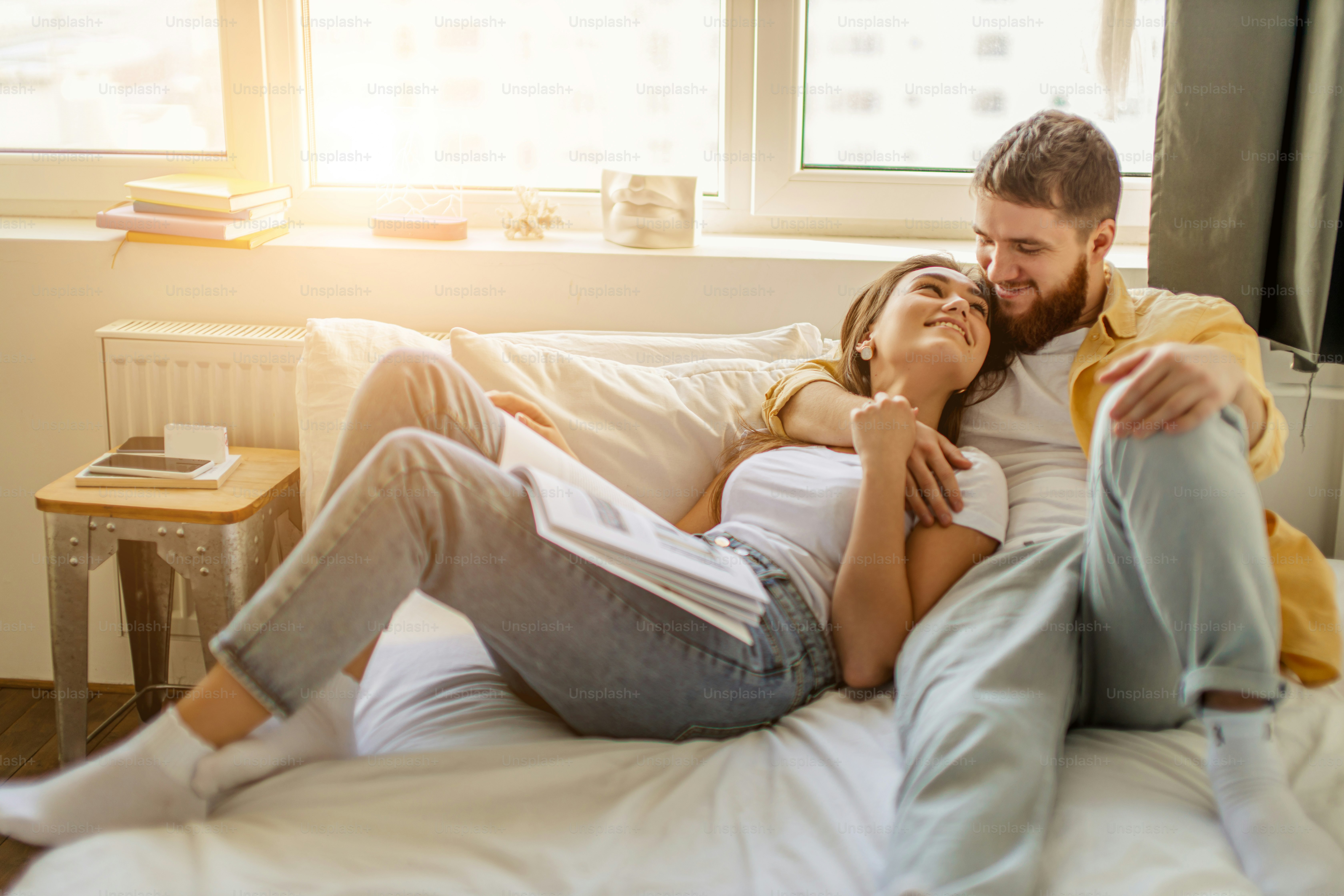 married caucasian couple relax and enjoy together at home, couple lie on bed have a rest, read books. weekends, holidays, leisure time concept