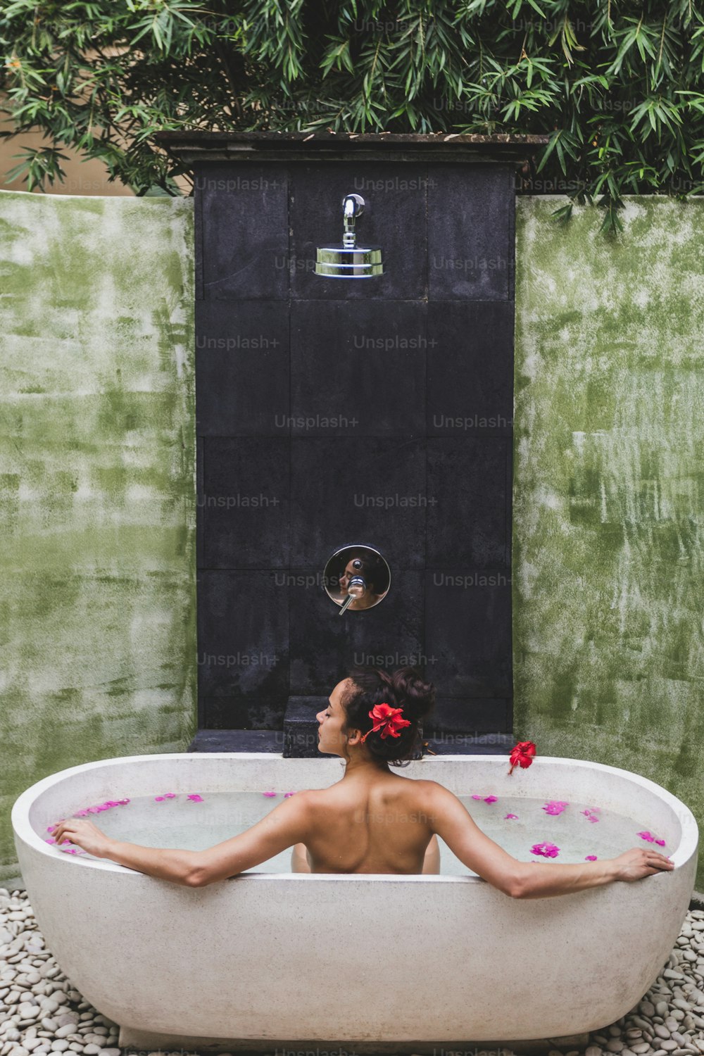 Mujer relajándose en un baño redondo al aire libre con flores tropicales, cuidado orgánico de la piel, hotel spa de lujo, foto de estilo de vida