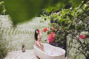 熱帯の花、オーガニックスキンケア、高級スパホテル、ライフスタイル写真で丸い露天風呂でくつろぐ女性