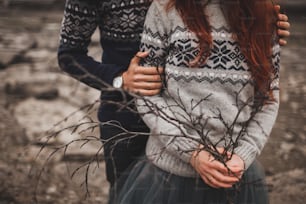 Traditional Icelandic autumn look. Handmade knitted gray and blue sweaters on woman and man couple. Conceptual branch bouquet.