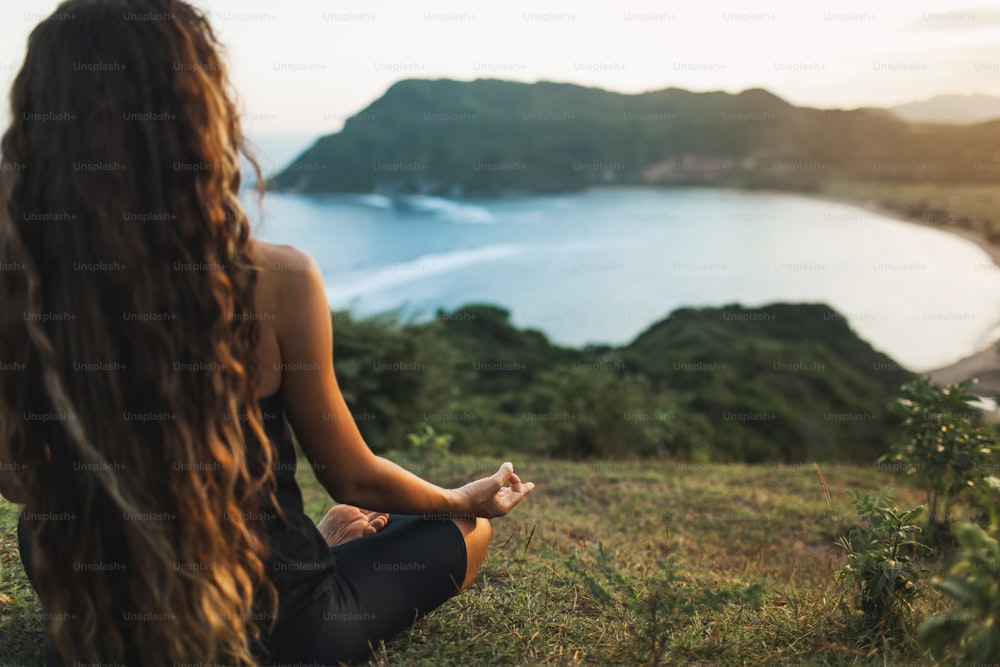 Donna che medita yoga da sola sulle montagne dell'alba. Vista da dietro. Concetto di rilassamento spirituale Travel Lifestyle. Armonia con la natura.