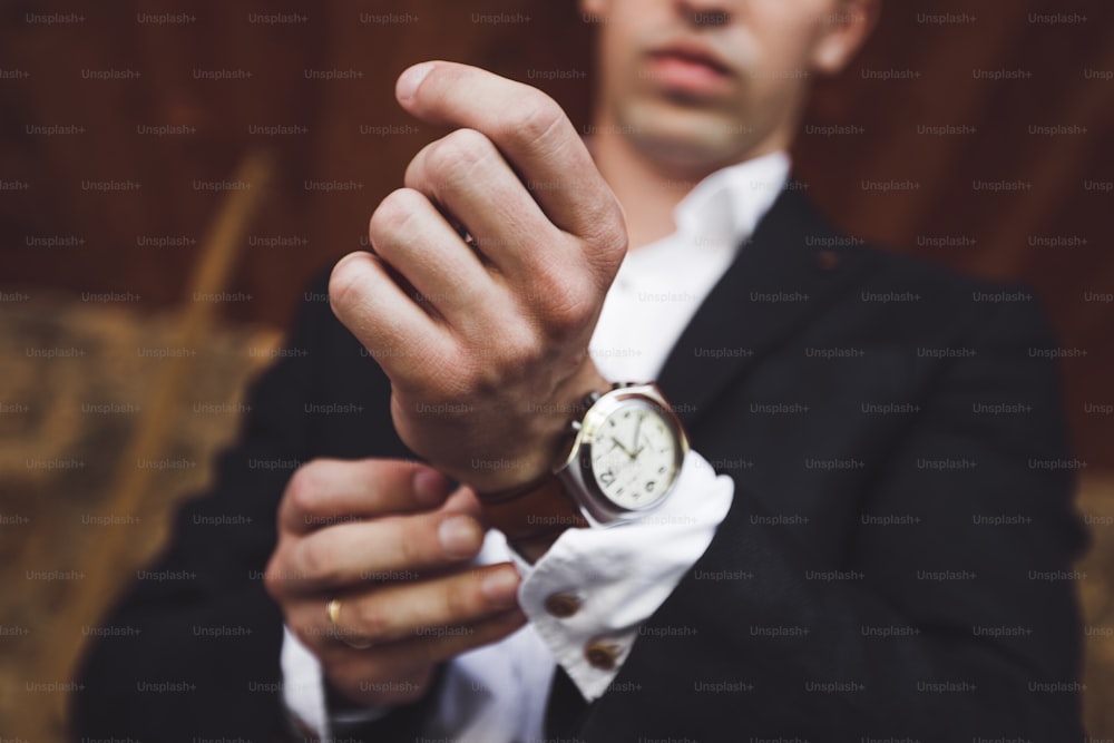 Mann im schwarzen Anzug trägt neue Uhren. Luxuriöser Stil
