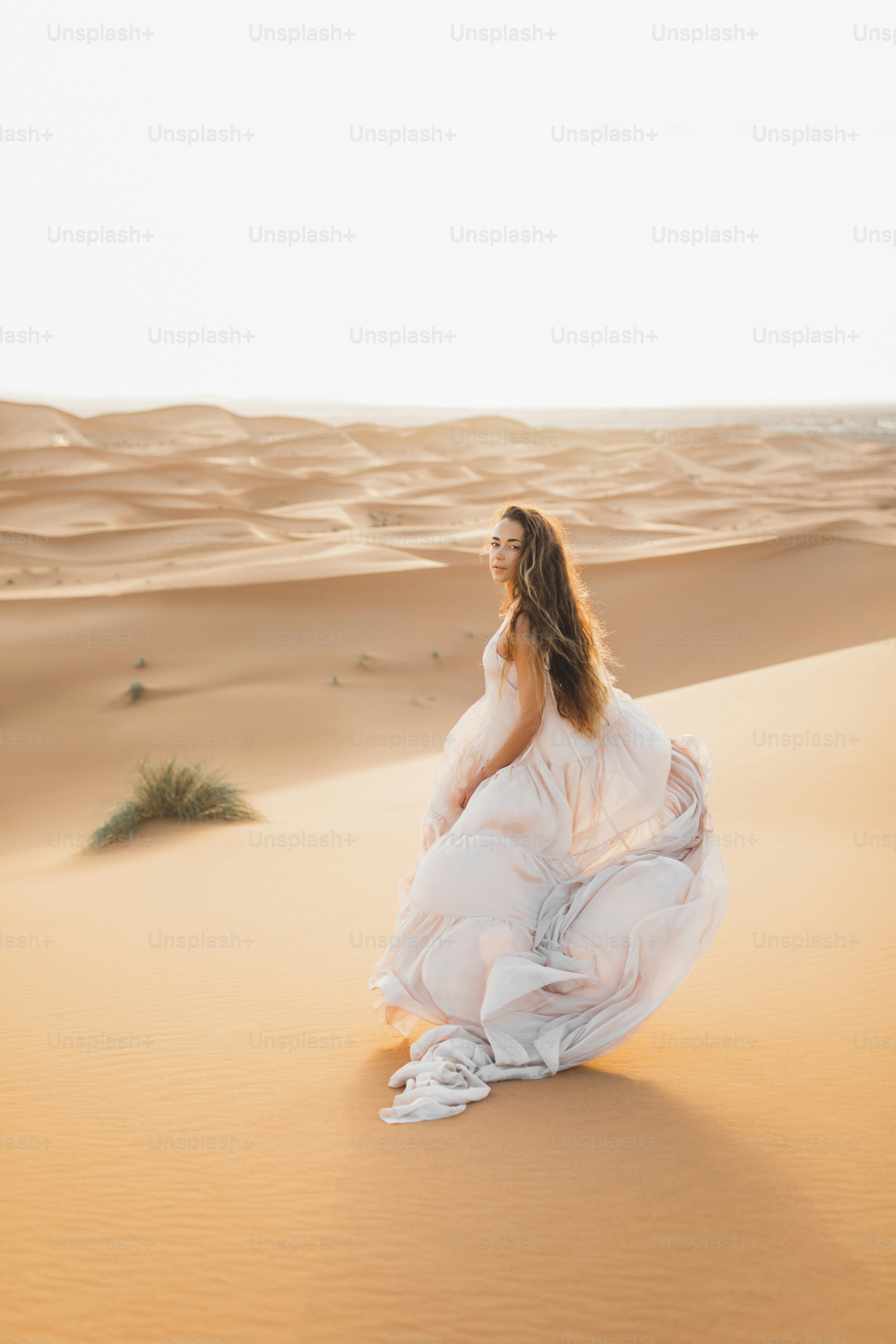 Portrait of bride woman in amazing wedding dress in Sahara desert, Morocco. Warm evening light, beautiful pastel tone, sand dunes on horizon.