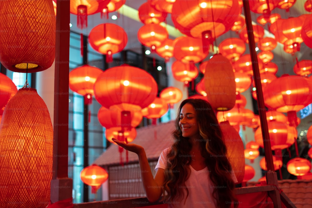 Glückliche Touristenfrau, die traditionelle rote Laternen genießt, die für das chinesische Neujahrsfest Chunjie geschmückt sind. Kulturelles asiatisches Festival in Peking.