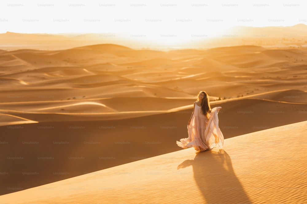 Ritratto della donna della sposa in abito da sposa incredibile nel deserto del Sahara, Marocco. Luce calda della sera, bella tonalità pastello, dune di sabbia all'orizzonte. Sfondo della natura.