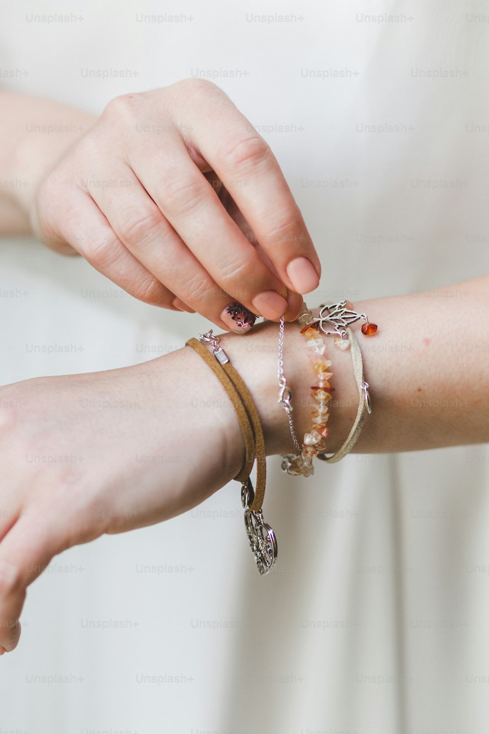 Mani di donna con diversi bracciali e gioielli