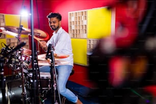 Atractivo baterista adolescente con baquetas en el estudio de grabación.