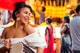 indian wearing fashionable clothes posing in asian bazar playing djembe music drummer.