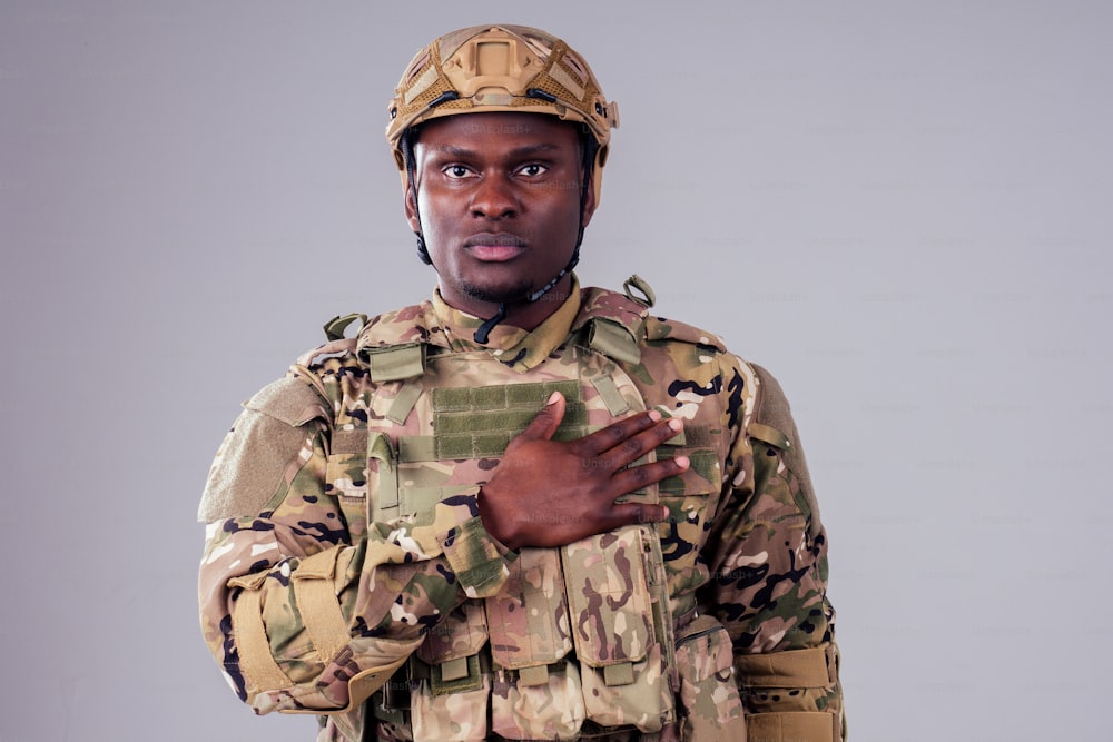 Soldato afroamericano con le braccia conserte in piedi nello studio bianco