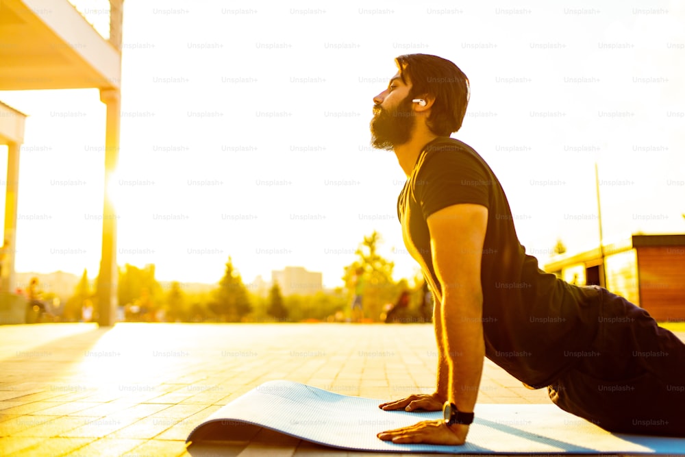 hispanic man in black cotton t-shirt ready to yoga at sunset in summer park outdoor golden lights.