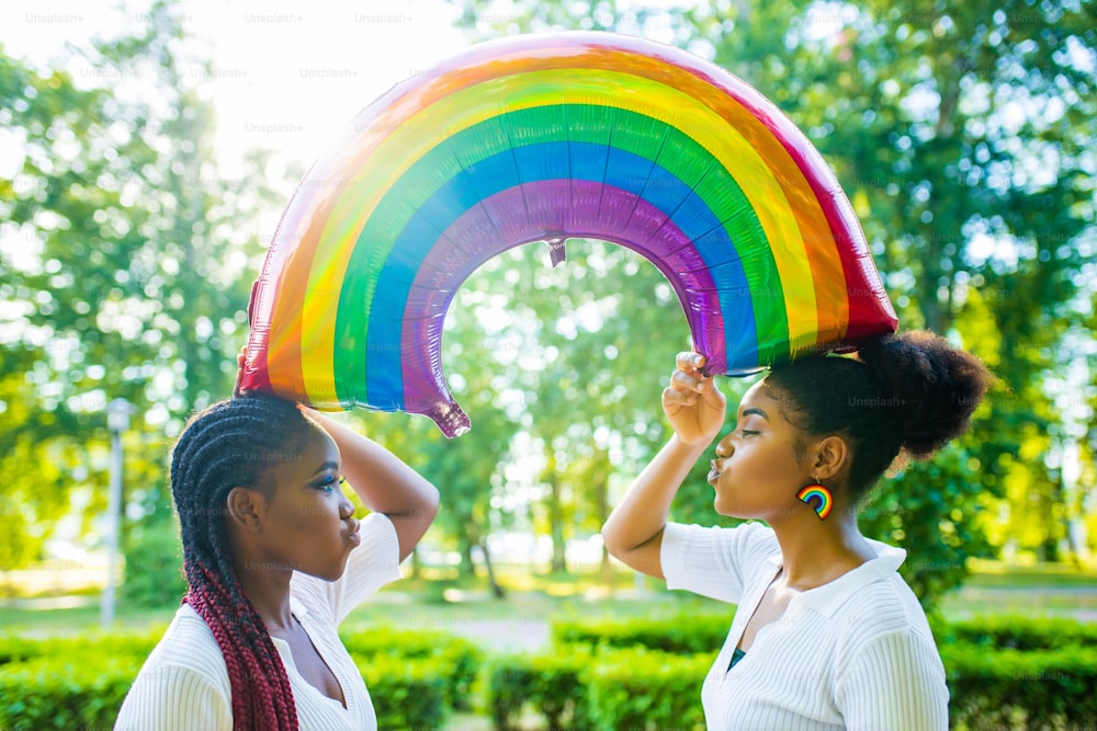 Due donne afroamericane che celebrano il matrimonio in abito wtite con maschio brillante in Summer Park.