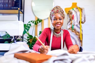 tanzanian woman with snake print turban over hear working in dressmaking shop .