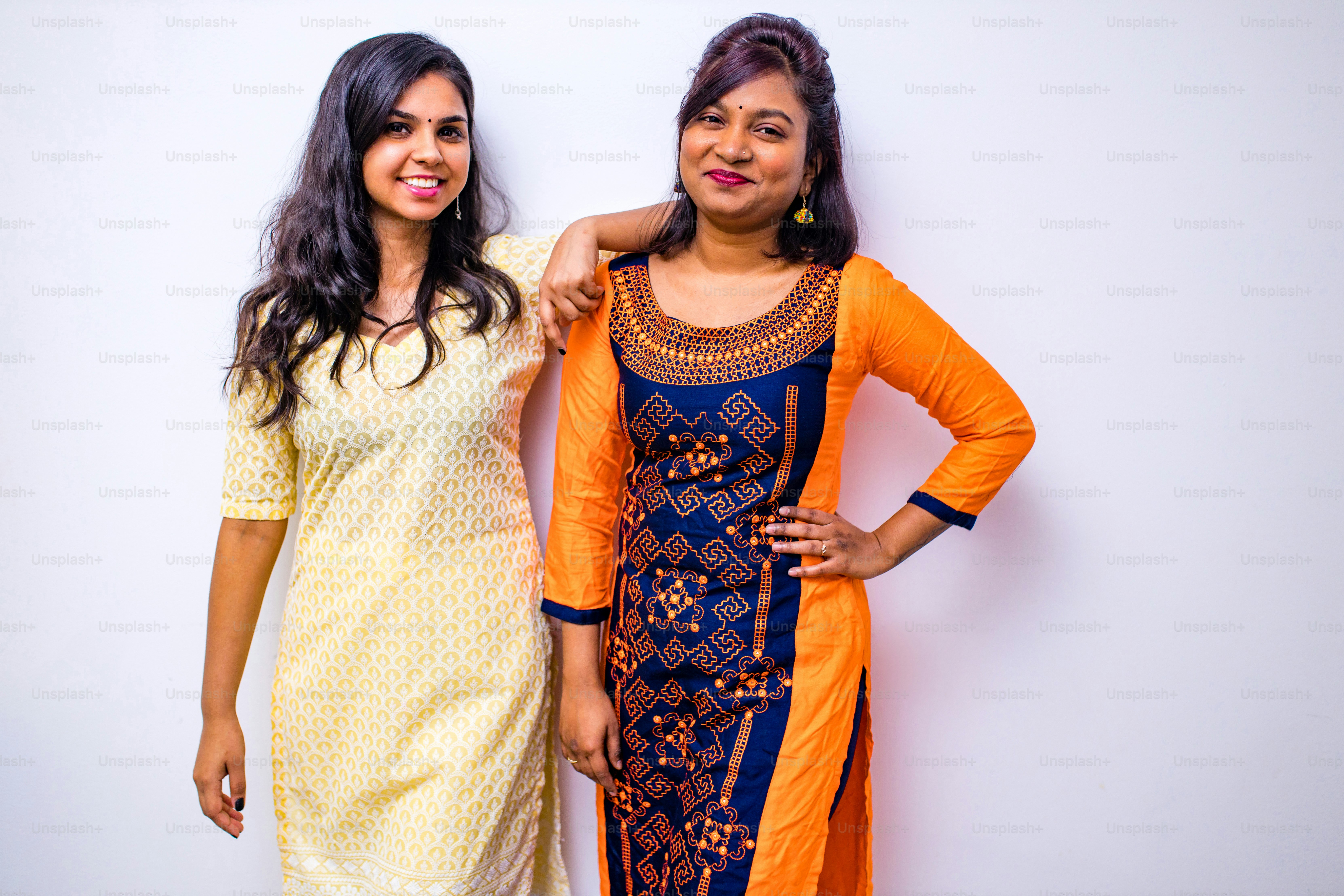 casual indian clothes ,two Indian woman in kurta posing over white wall.