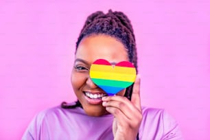 afro american woman holding a heart shape in pink studio background.