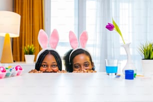 duas irmãs felizes com orelha de coelho pintando ovos no apartamento se preparando para a Páscoa.