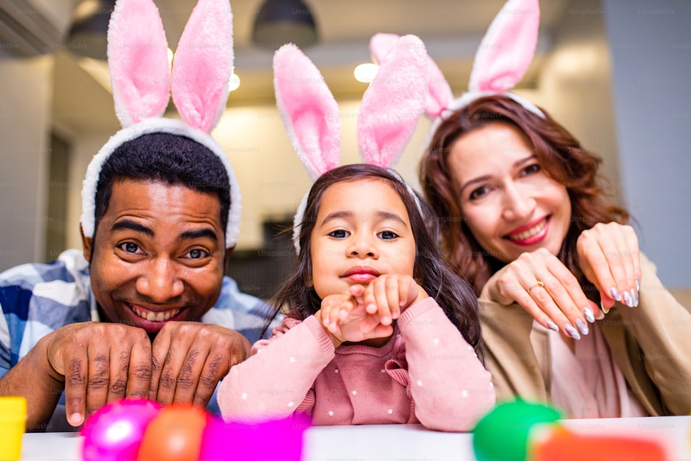familia de raza mixta coloreando huevos de Pascua en la sala de estar.
