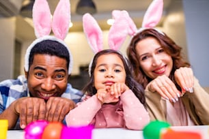 mixed race family coloring Easter eggs in living room.