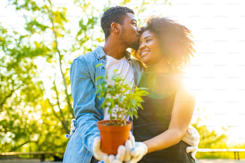 afro americano casal jardinagem ao ar livre ao pôr do sol ensolarado dia de primavera.