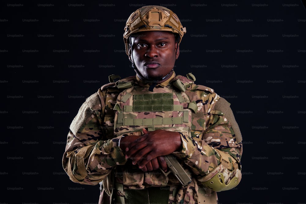 Soldat afro-américain aux bras croisés debout dans un studio blanc