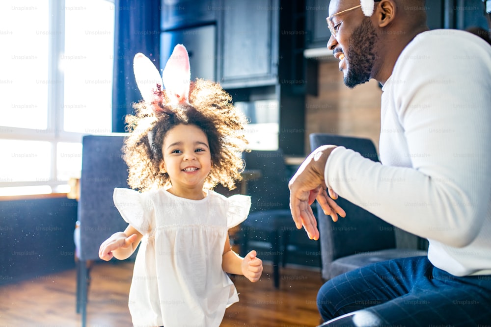 authentic ethnic multicultural people wearing bunny ears in living room day sunlight.