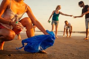 Concéntrese en una niña alegre que limpia la playa de arena de la basura con sus amigos en el equipo de voluntarios de fondo en el movimiento ecológico en Goa, India.