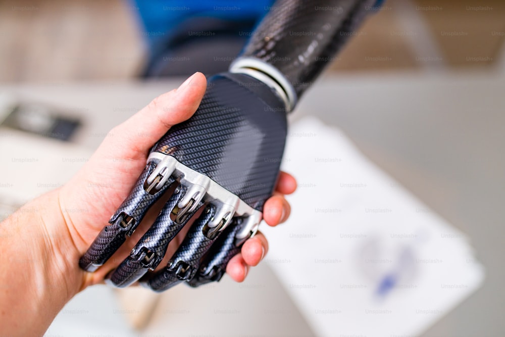 Handshake between hand of human and robot hand isolated on office background.