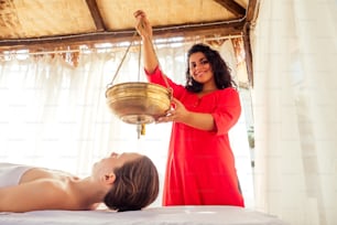 mujer joven haciendo tratamiento tradicional indio de salud en el centro de constitución corporal Ayurveda.
