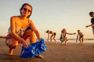 concentrarsi sulla ragazza allegra che pulisce la spiaggia sabbiosa dalla spazzatura con i suoi amici sul team di volontari di sfondo sul movimento eco-compatibile a Goa in India.