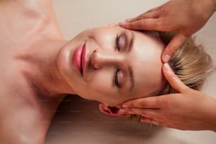 스파에서 아름다움 금발의 글래머 여성 눈을 감고 스파 센터에서 머리 마사지를 즐기다 전문 치료 건강 스트레스 치료 애지중지하는 얼굴 아름다움 피부:여드름 방지 및 주름 방지