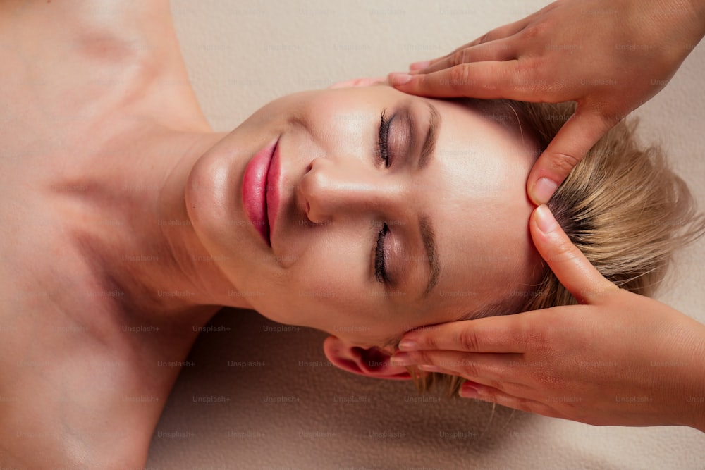 beauté blonde glamour femme dans spa yeux fermés profiter massage de la tête au centre de spa thérapie professionnelle traitement du stress soins de santé soin du visage beauté peau:anti acné et anti rides