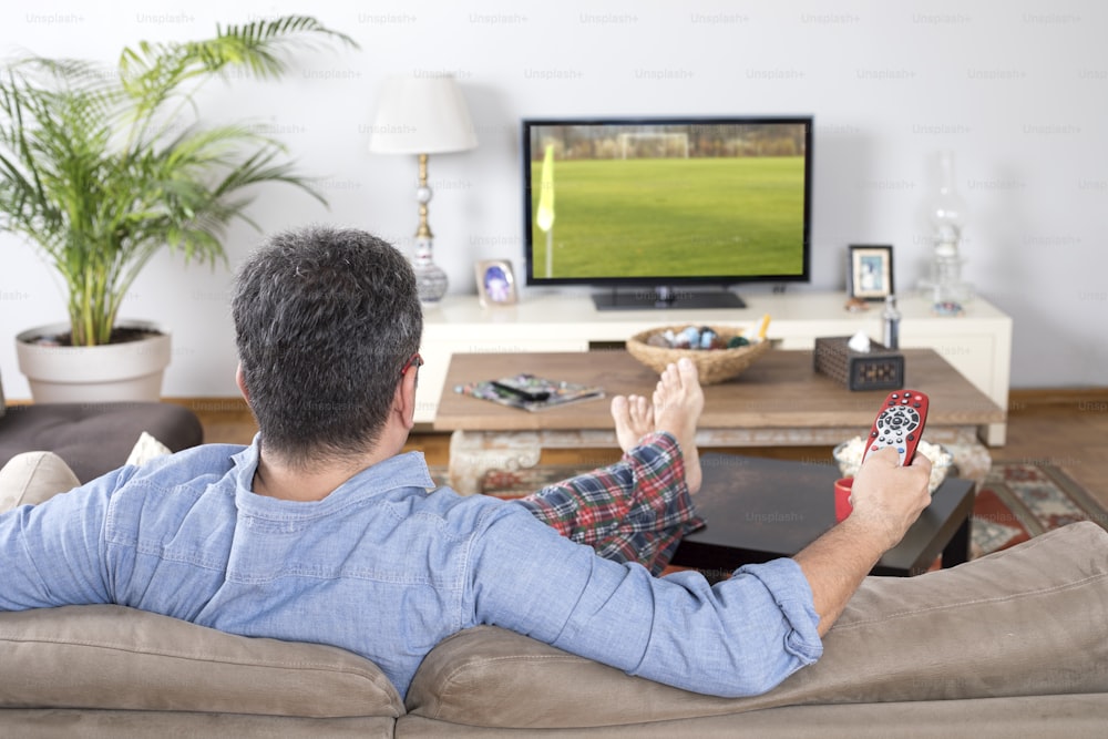 テレビでスポーツを見ている男性