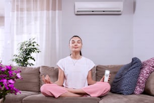 Frau mit Fernbedienung der Klimaanlage