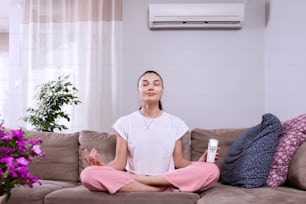 woman using remote control of air conditioner