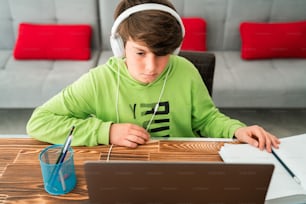 Young boy is studying in front of the laptop. E learning, study at home online