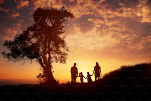 Siluetta di famiglia felice in piedi contro l'ora del tramonto.