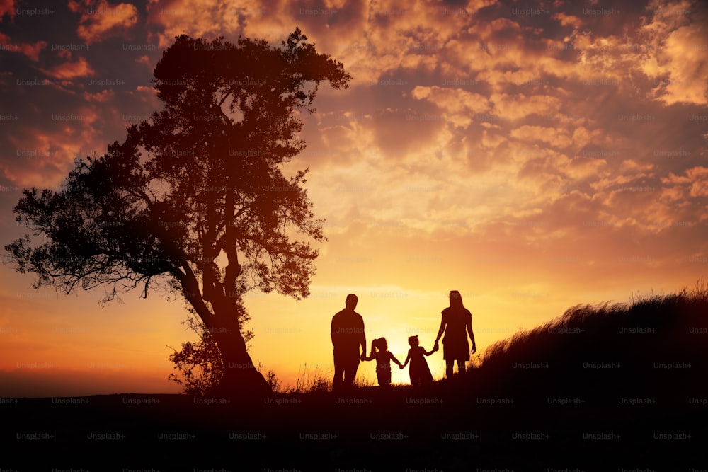 Glückliche Familiensilhouette, die gegen Sonnenuntergang steht.